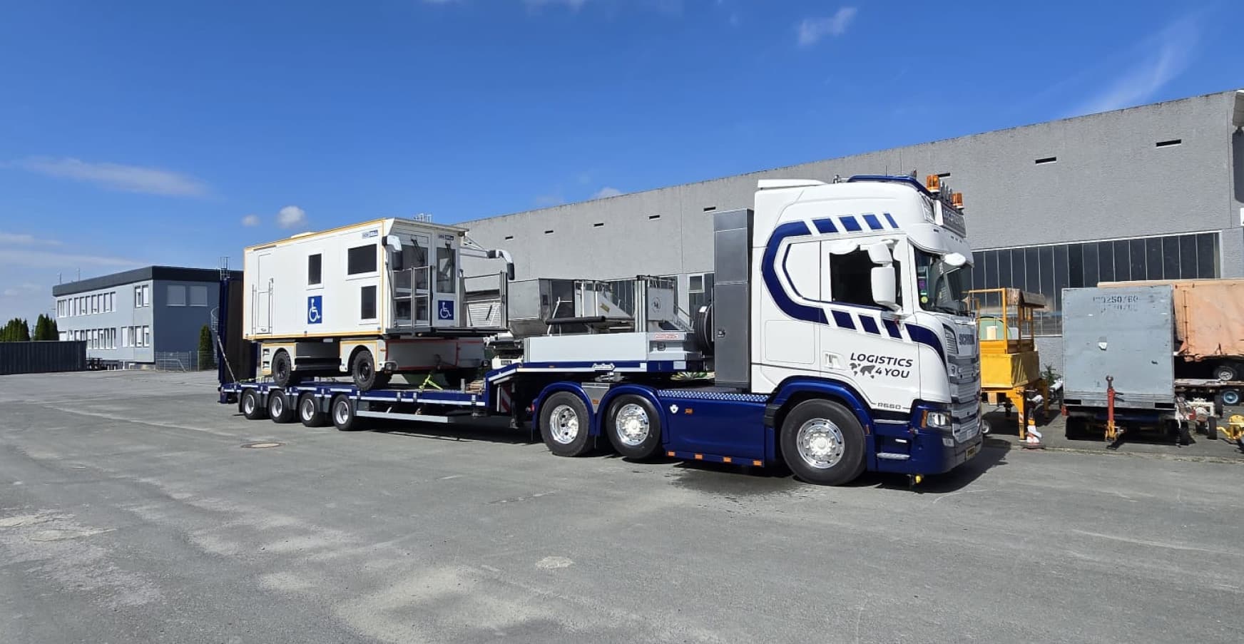 A Logistics4You Scania tractor unit at the yard with an airport passenger-boarding unit loaded on a four-axle low-loader